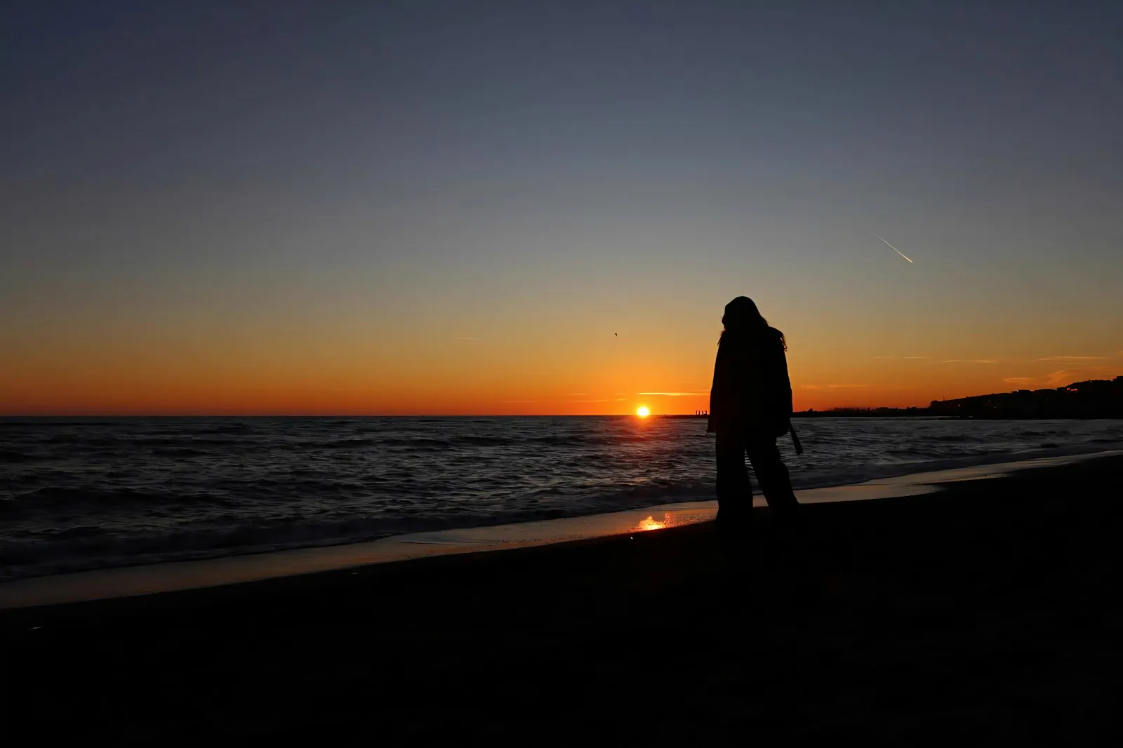 夕日の海辺に立つ人